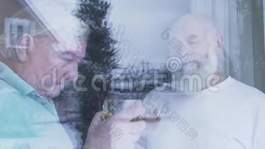 两个喝着酒精威士忌的老人站在家窗户附近。 白种人老人和朋友在<strong>享受时光</strong>
